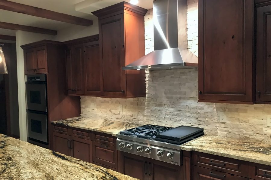 Dark wood kitchen with pro range and stacked-stone backsplash